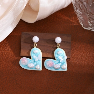 Detailed close-up of heart-shaped floral drop earring with pearls and pink flowers