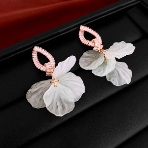 Macro detail of rose gold flower earrings with white petals and shimmering crystals