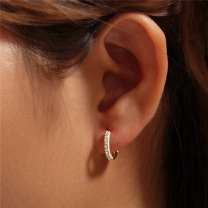 Close-up of gold-plated hoop earring with sparkling white cubic zirconia pavé stones