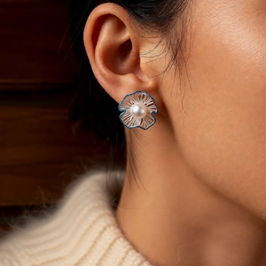 Detailed close-up of a silver floral earring with white pearl and navy blue accents