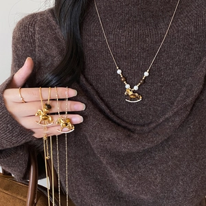 Detail of a gold rocking horse pendant necklace with tiger eye stone and pearls