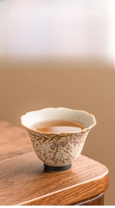 Detail of hand-painted wisteria flower on ceramic tea cup with wavy petal gold-rimmed edge