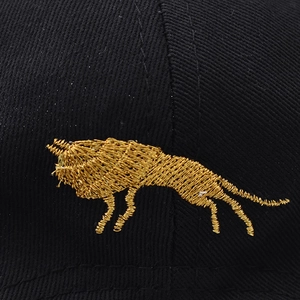 Close-up of golden lion embroidery on black cotton baseball cap with twill texture