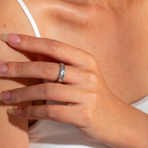 Detail of silver titanium steel ring with embossed patterns worn on the index finger