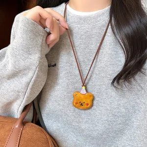Dettaglio del ciondolo a forma di orsetto marrone in resina con cappellino rosa su collana