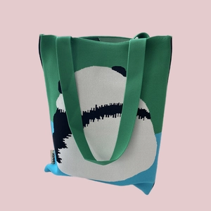 Detail of knitted tote bag showing green and white stripes with a panda pattern design