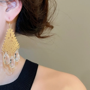 Detailed close-up of vintage gold hollow geometric earrings with crystal teardrop tassels