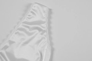 Detailed view of white satin fabric and delicate eyelash lace trim on a sexy dress