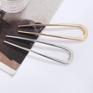 Pair of minimalist gold and silver U-shaped metal hairpins displayed on white background