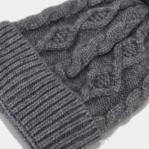Detailed macro view of dark grey cable knit pattern and ribbed cuff on winter hat