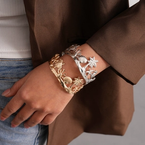 Detail of gold and silver open bangles featuring tropical sea turtles and starfish designs