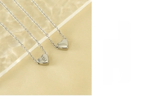 Detail of silver heart necklace featuring an engraved letter E with polished finish
