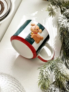 Detail of a Christmas ceramic mug with red stripes and a 3D teddy dog relief on a festive branch