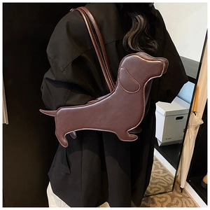 Detail shot of the dachshund-shaped dark brown leather crossbody bag worn by a model