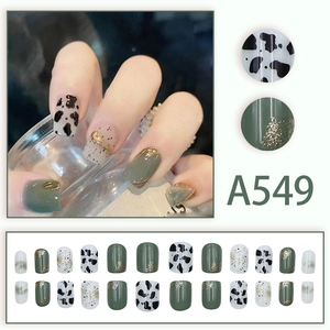 Green translucent press-on nails with cow print and glitter details in 24-piece set