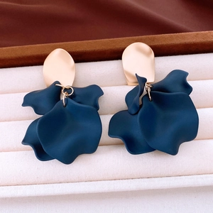 Macro shot of dark blue matte petal pendant earrings with gold studs in a velvet box