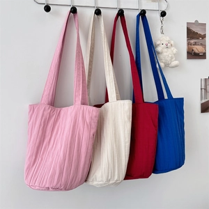 Bolsos tote con pliegues verticales en rosa, beige, rojo y azul colgados en ganchos