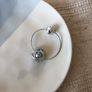 Detail of silver bangle with rose flower and spherical bead on a ceramic dish