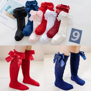 Detail of baby knee-high socks featuring cable knit patterns and satin ribbon bows