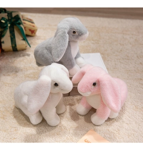 Three plush bunny dolls in grey white and pink sitting on carpet for home decoration