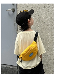 Detail of yellow canvas kids belt bag with adjustable black strap and blue logo patch