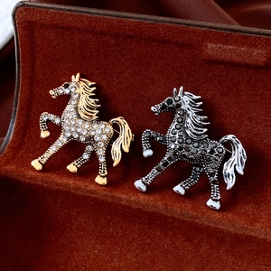 Macro shot of gold and silver horse brooches with sparkling rhinestones in a velvet box