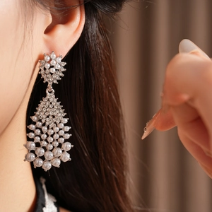 Close-up of vintage silver tassel earrings with pearls and rhinestones on a model