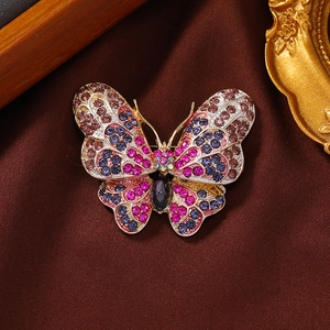 Sparkling butterfly brooch pin with multicolored rhinestones on a brown satin background