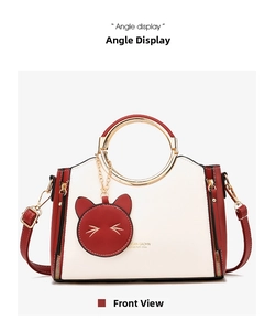 Detail view of red and white tote bag with golden ring handle and cat pendant decoration