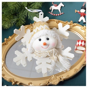 Close-up of plush snowman ornament with knitted hat on a festive gold mirror tray