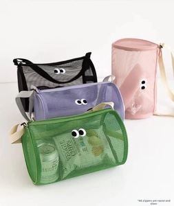 Detail of four colorful mesh toiletry bags showing large eye embroidery and silver zippers