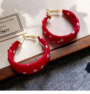Detail of vintage red fabric hoop earrings with white polka dots on soft textured cloth