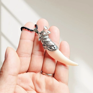 Detail of faux wolf tooth resin pendant with vintage silver cap on a black cord