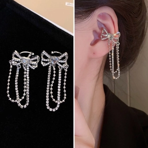 Détail de manchette d'oreille nœud argenté avec pompons strass sur modèle et fond noir
