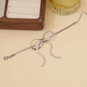 Close-up of a silver bow bracelet featuring a sleek snake chain and adjustable clasp