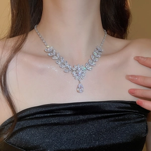 Detail of silver drop necklace with zircon leaf and flower pendant on model neck