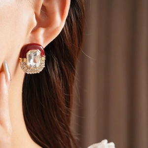 Close-up of vintage oval earring with dark red enamel, gold plating and crystals