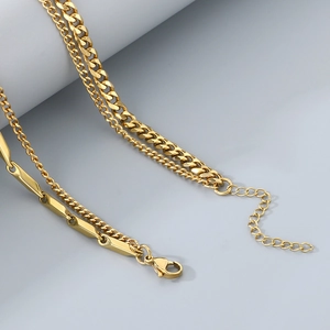 Detail of double-layered gold snake chain and bar link necklace with lobster clasp