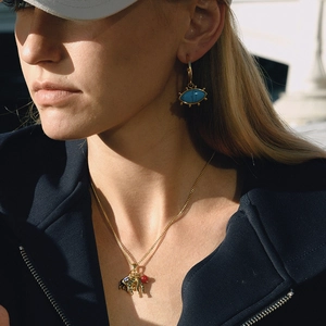 Close-up of gold evil eye earrings and elephant pendant necklace on a model