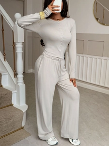 Detail view of women's beige two-piece set featuring button-up shirt and wide-leg trousers