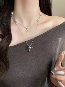 Macro detail of silver double-layered necklace with pearl and planet zircon pendants