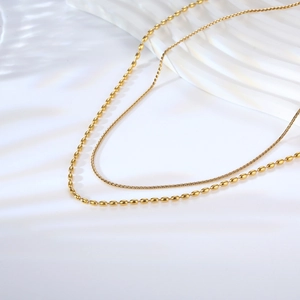 Detail of layered gold titanium necklace showing olive bead chain and fine twisted link