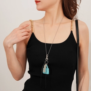 Détail d'un pendentif sac à main en cristal bleu brillant sur une chaîne à perles argentée