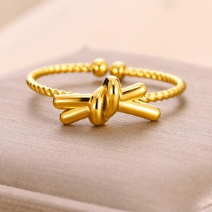 Macro detail of gold knot ring featuring a twisted band design and adjustable open fit
