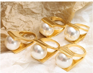 Detailed view of Y-shaped 18k gold plated titanium rings with large round pearls
