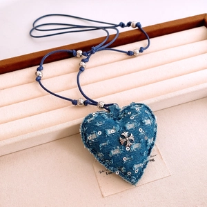 Détail du pendentif cœur en denim vintage avec paillettes argentées et croix en métal