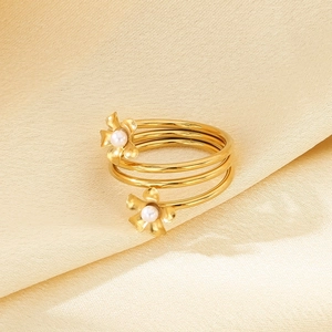 Detail of spiral gold ring with pearl flowers on elegant yellow silk fabric surface