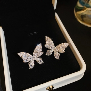Gros plan de boucles d'oreilles papillon en argent avec zircons sur velours noir