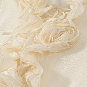 Detailed view of off-white 3D pleated fabric flower with intricate texture on dress sleeve