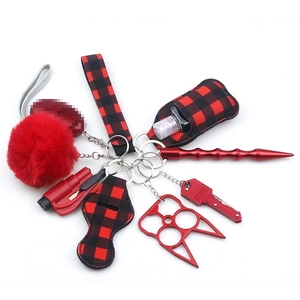 Macro view of red buffalo plaid keychain set with pompom and safety accessories
